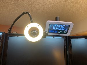ring light with googly eyes next to clock on top of computer screen