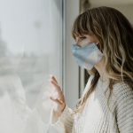 woman with medical mask looking out window
