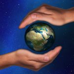earth surrounded by two human hands and outer space background