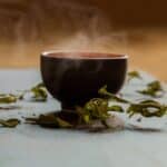steaming cup of tea, surrounded by tea leaves